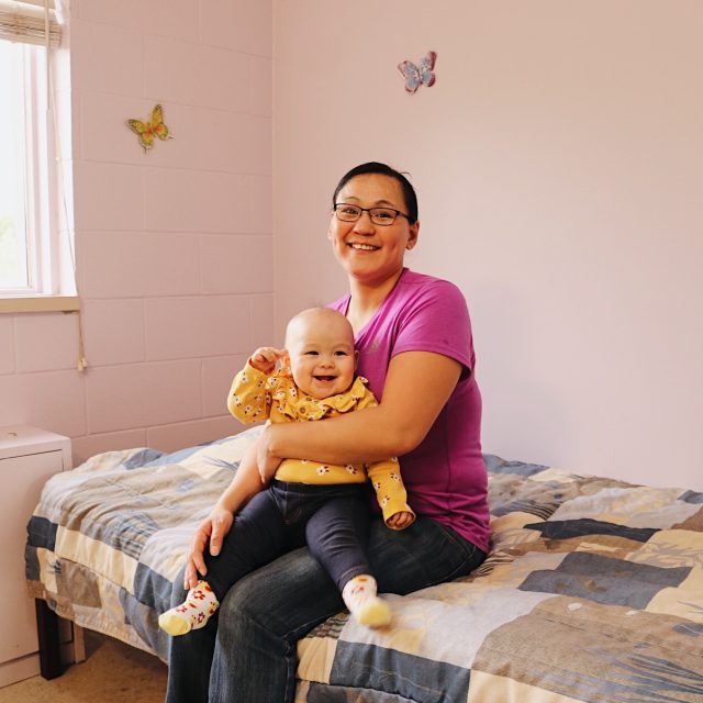 Mother and baby sitting on bed