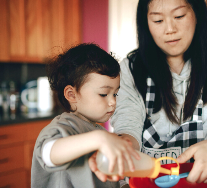Mother and child in kitchen measuring ingredient
